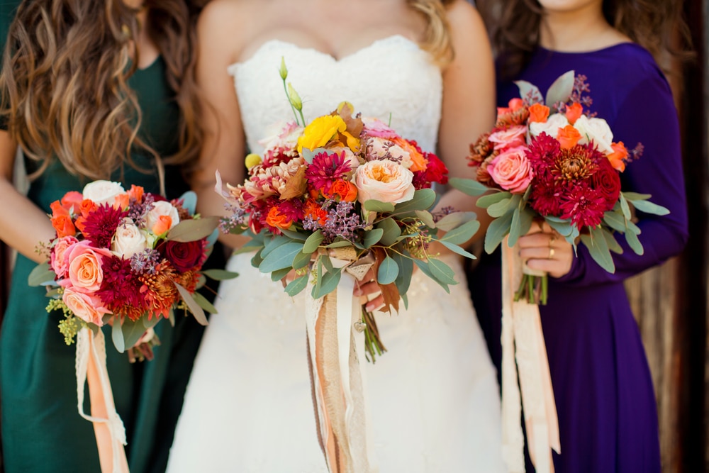 Bride and bridesmaids holding bouquets in MInnesota fall colors at one of the best Stillwater wedding venues.